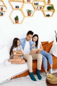 A loving family of three reading together on a cozy sofa, enjoying quality time at home.