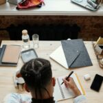 Overhead view of a student studying at a desk with notebooks, phone, and coffee.